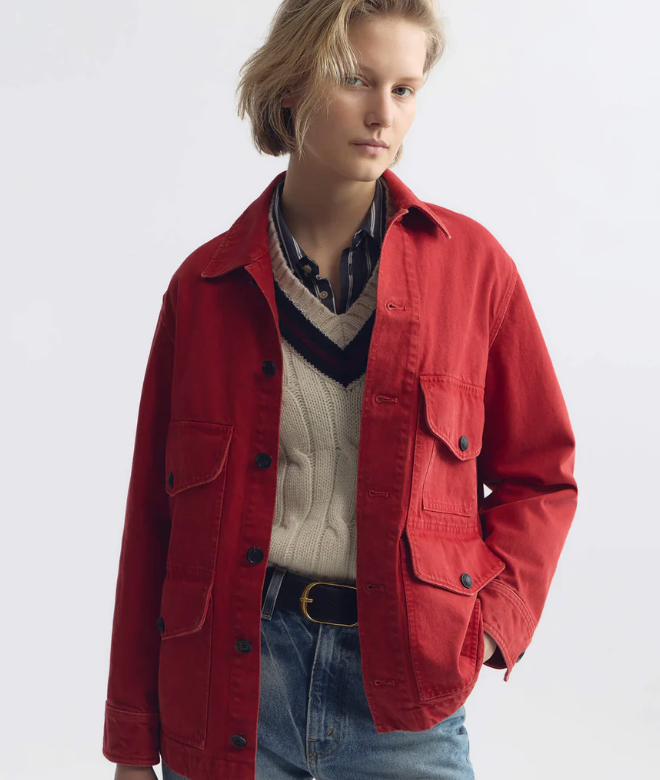 Person wearing a red jacket over a sweater and jeans on a white background