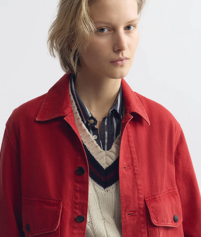 Person wearing a red jacket over a sweater with a white background