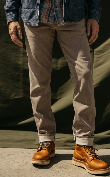 Person wearing beige pants and brown boots standing on a concrete surface with a blurred background.