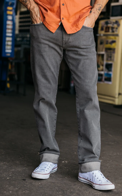 Person wearing gray jeans and white sneakers in a workshop setting
