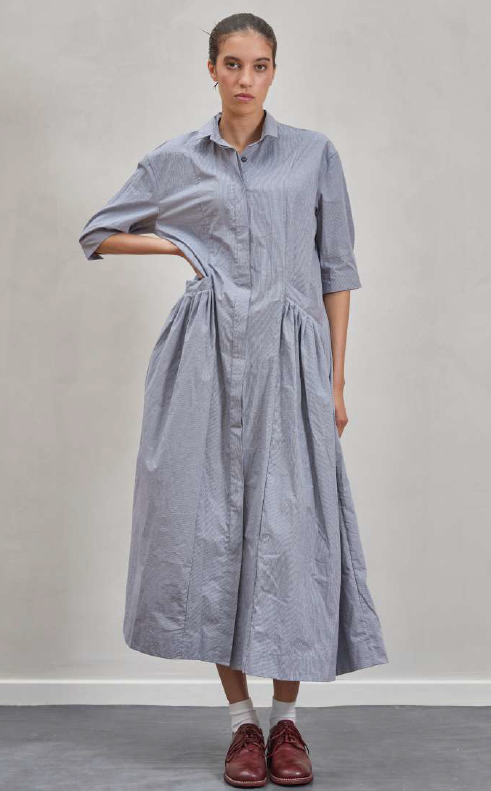 Woman wearing a long blue dress with a plain background