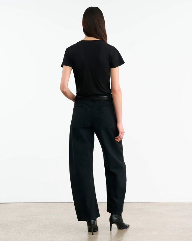 Person wearing a black outfit with wide-leg pants against a white background