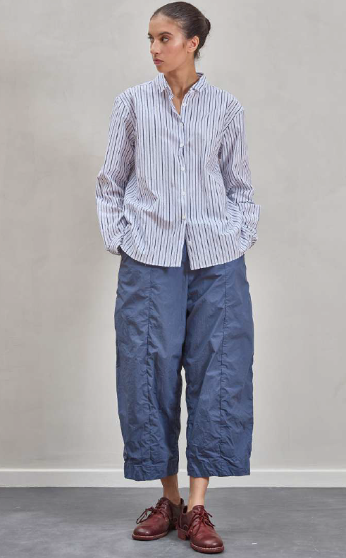 Person wearing a striped shirt and blue pants against a plain background