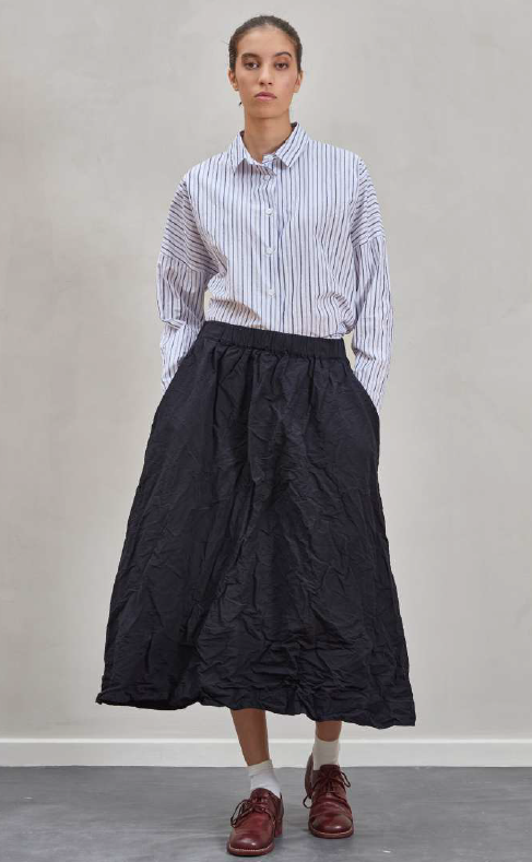 Person wearing a striped shirt and black skirt on a plain background