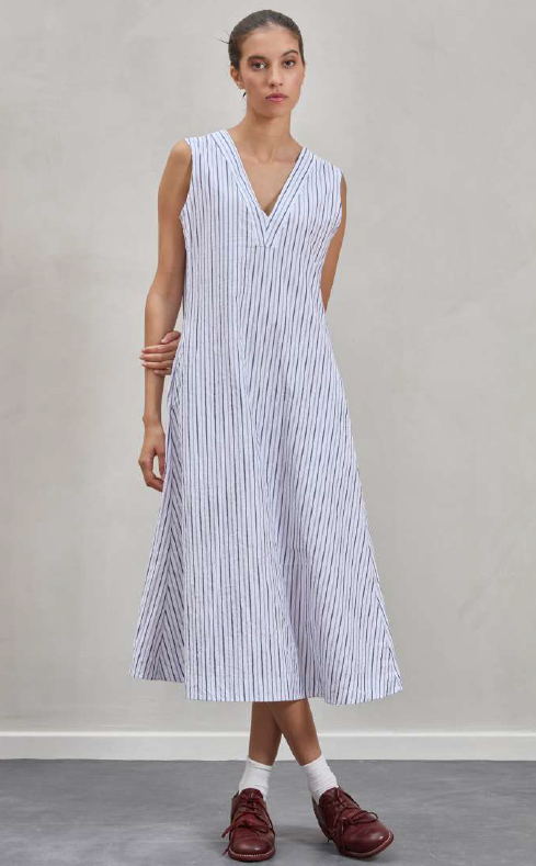 Woman wearing a sleeveless striped dress against a plain background