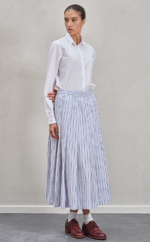 Woman wearing a white blouse and striped skirt against a plain background