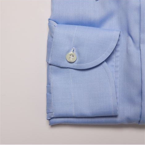 Folded light blue shirt with a button on a light gray background