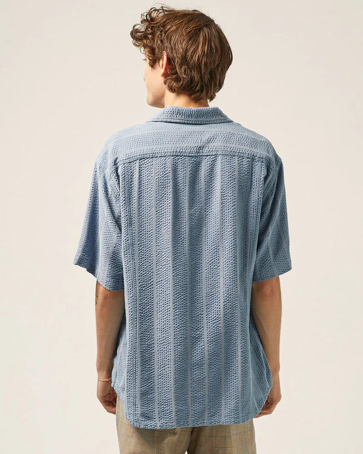 Person wearing a textured blue shirt against a plain background