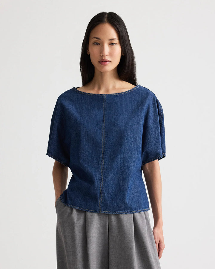 Woman wearing a blue denim top and gray skirt on a white background