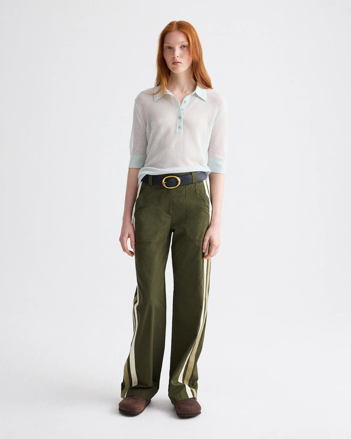 Woman wearing a white shirt and green pants with white stripes on a white background