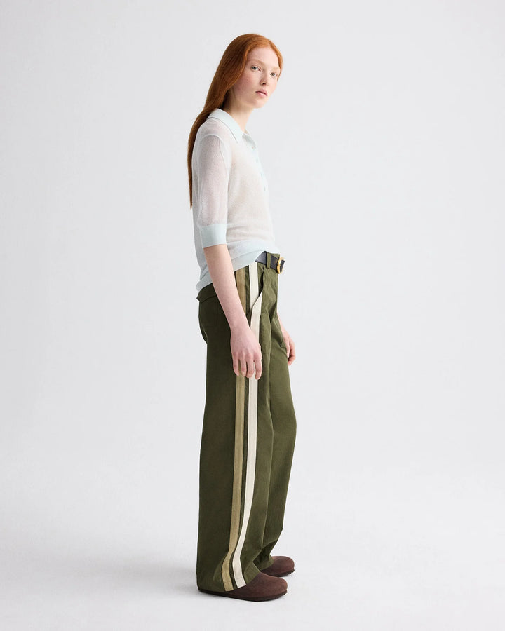 Woman wearing a white top and green pants with a stripe on a white background