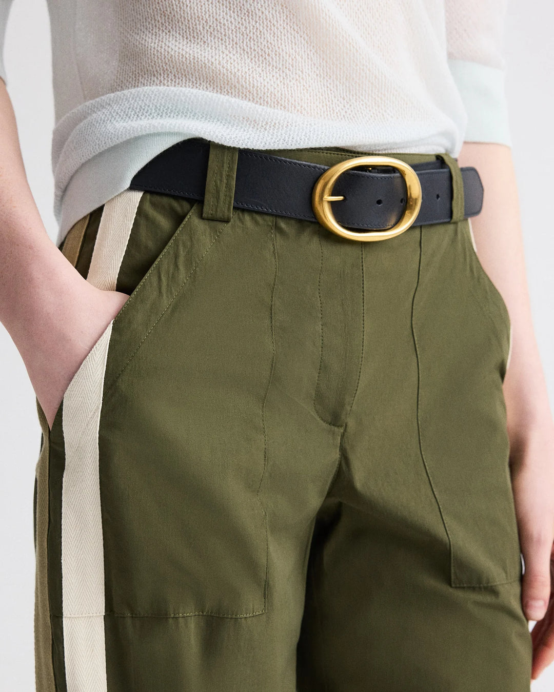 Person wearing green pants with a black belt and gold buckle.