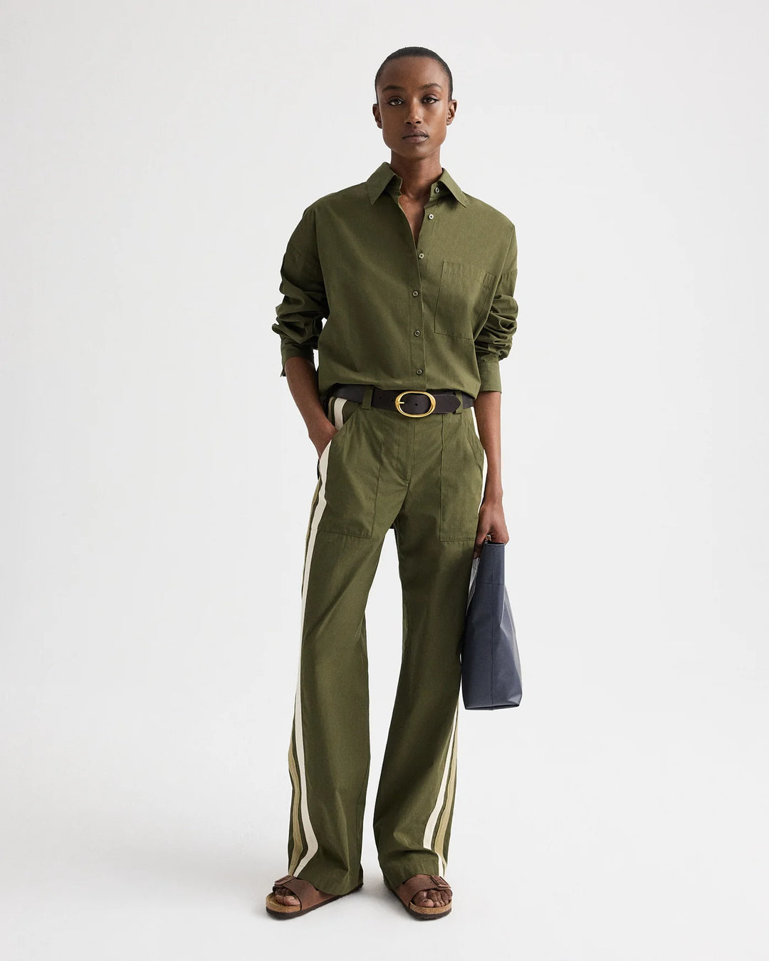 Person wearing a green shirt and pants with a white background