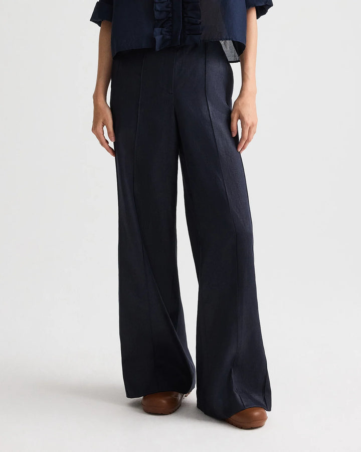 Person wearing navy blue wide-leg pants on a white background