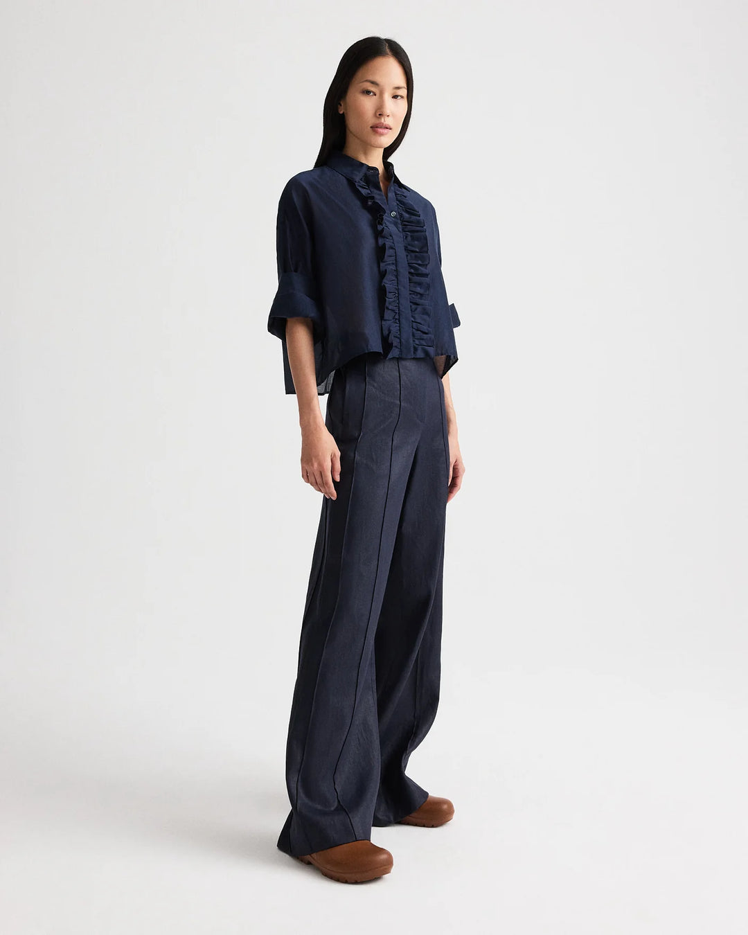 Woman wearing a dark blue shirt and wide-leg pants on a white background