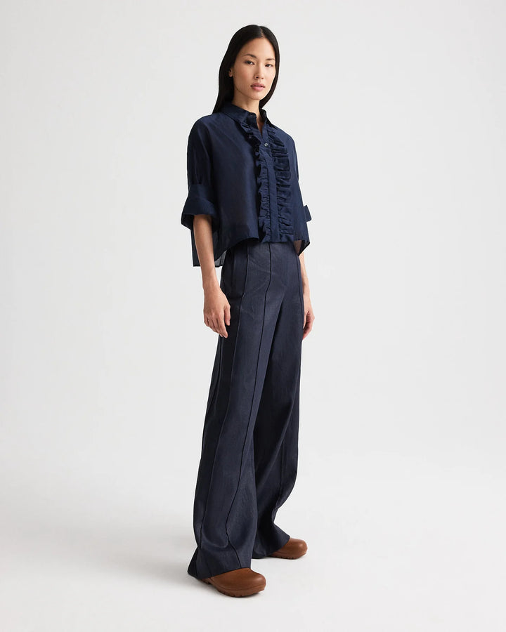Woman wearing a dark blue shirt and wide-leg pants on a white background