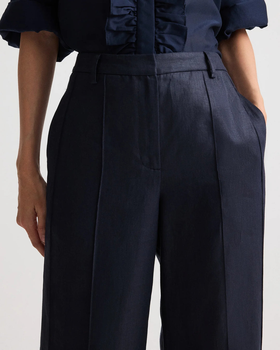 Navy blue pants worn by a person on a light gray background