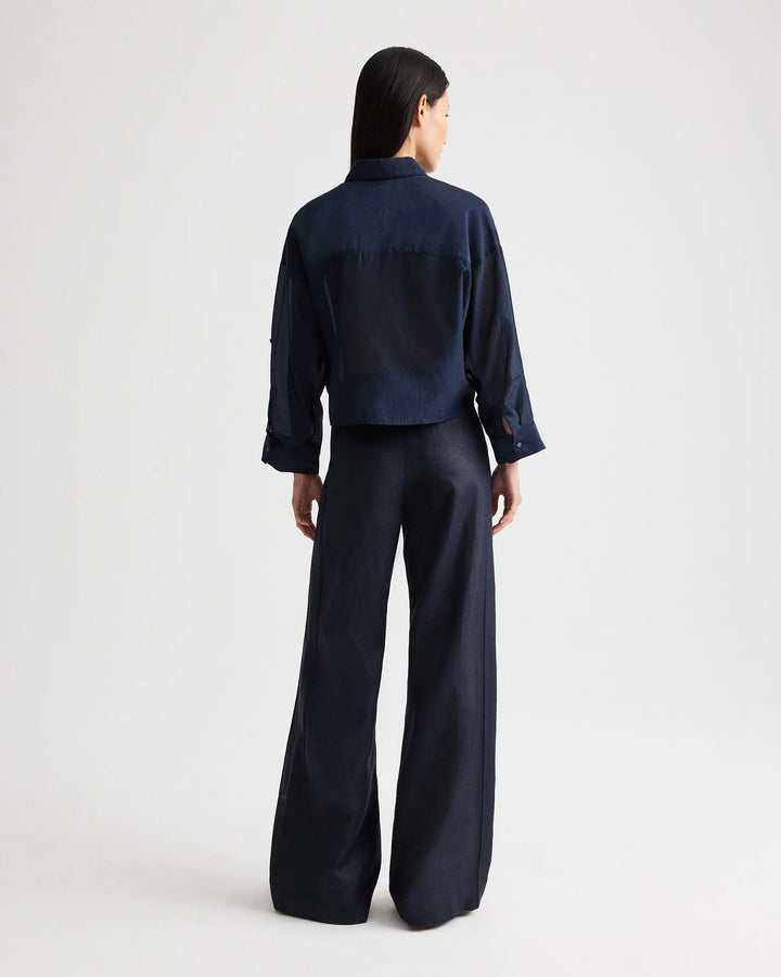 Person wearing a navy blue outfit with wide-leg pants on a white background