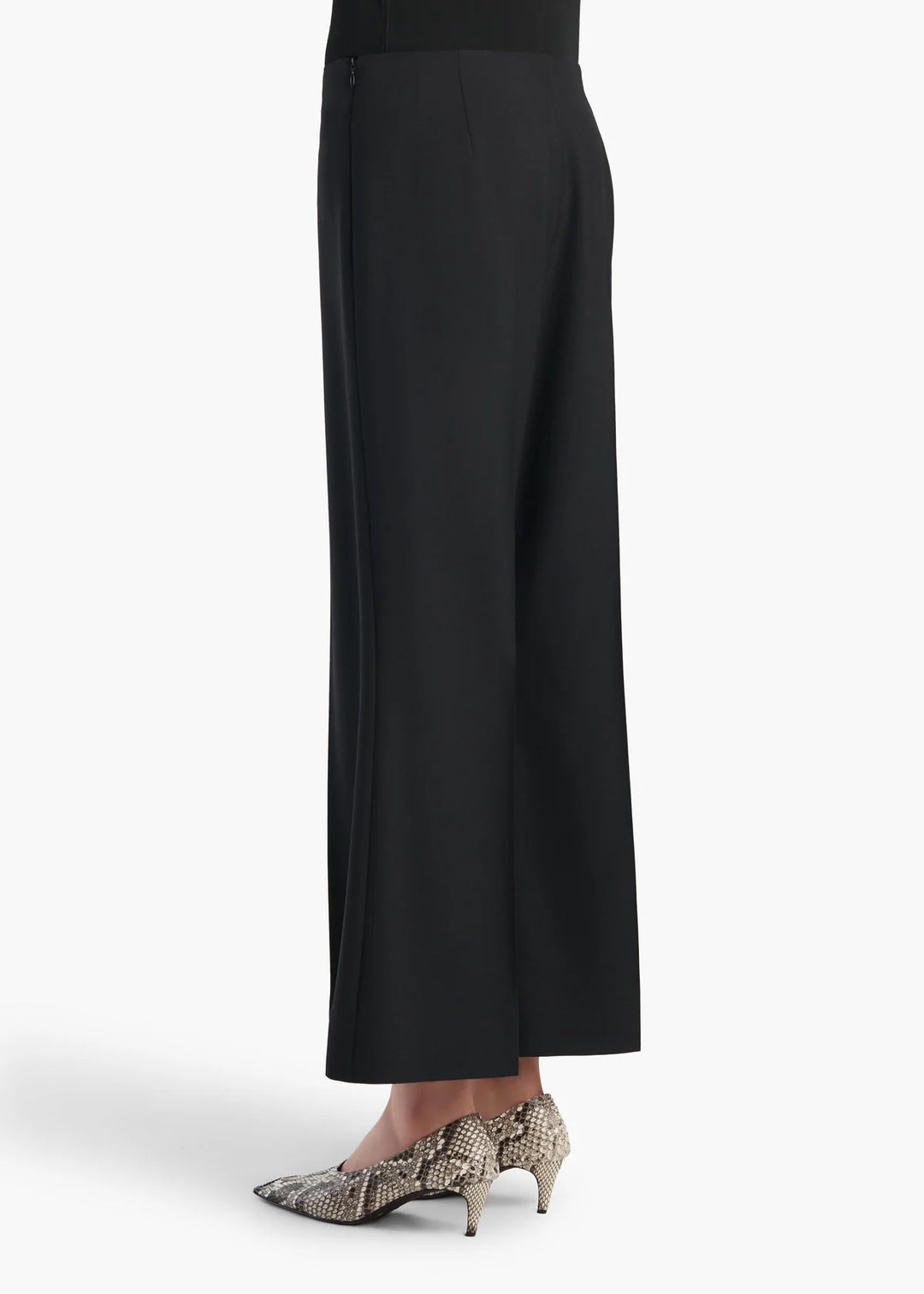 Black wide-leg cropped pants shown on a model from the waist down, paired with snakeskin-patterned pointed-toe heels against a plain white background.