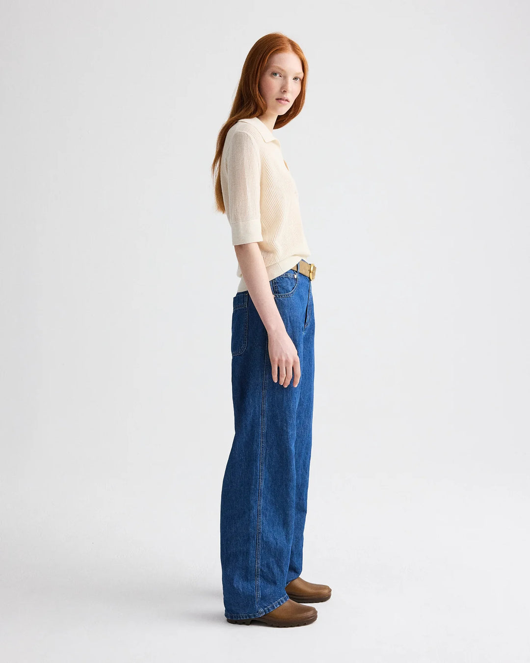 Woman wearing a white top and blue jeans on a white background