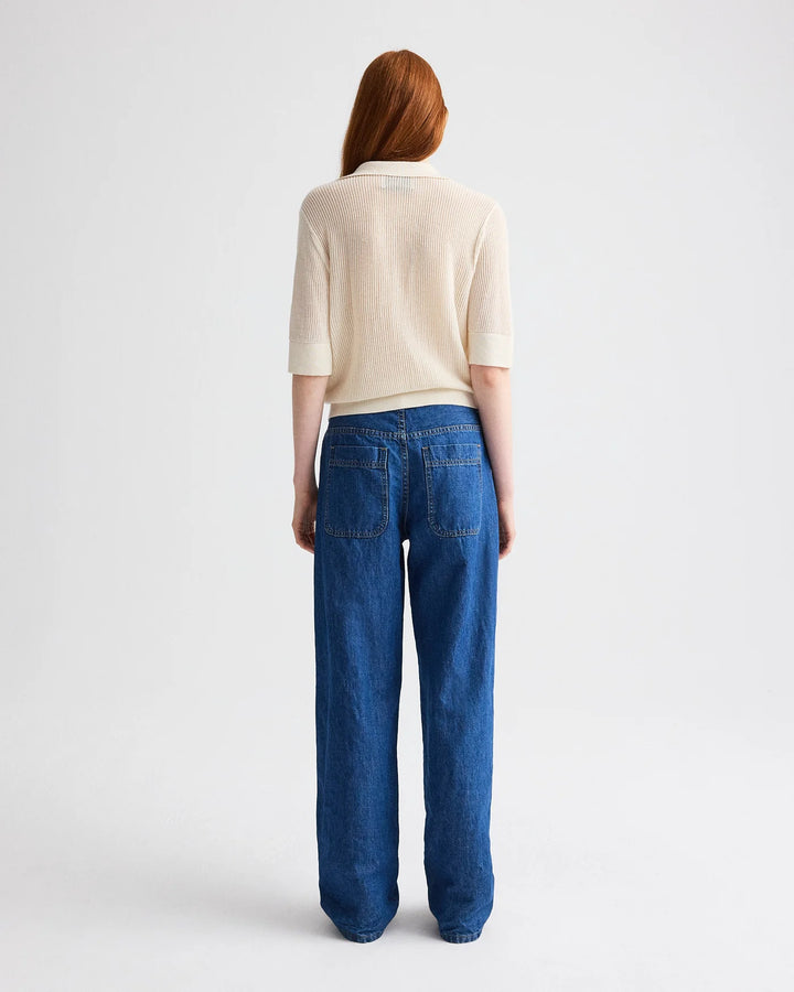 Person wearing a beige top and blue jeans on a white background