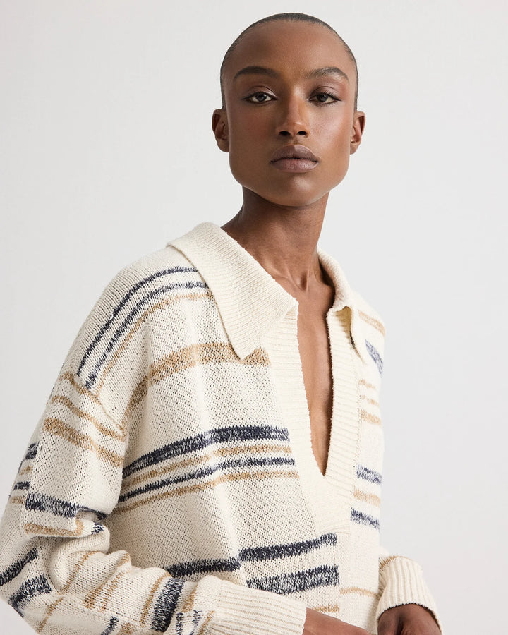 Woman wearing a cream-colored cardigan with blue and brown stripes on a white background