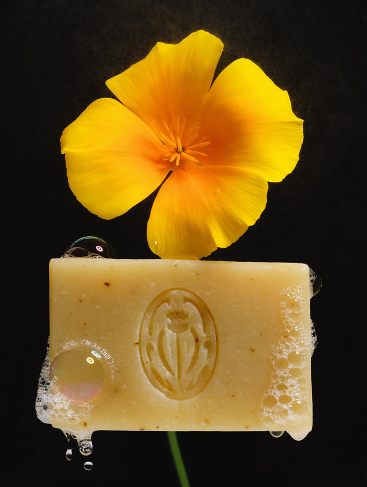 Bar of soap with a yellow flower on top against a black background