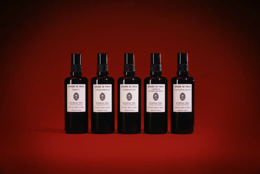 Five black spray bottles with white labels on a red background