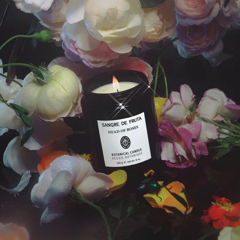 Sangre de Fruta candle with 'Head of Roses' label surrounded by colorful flowers