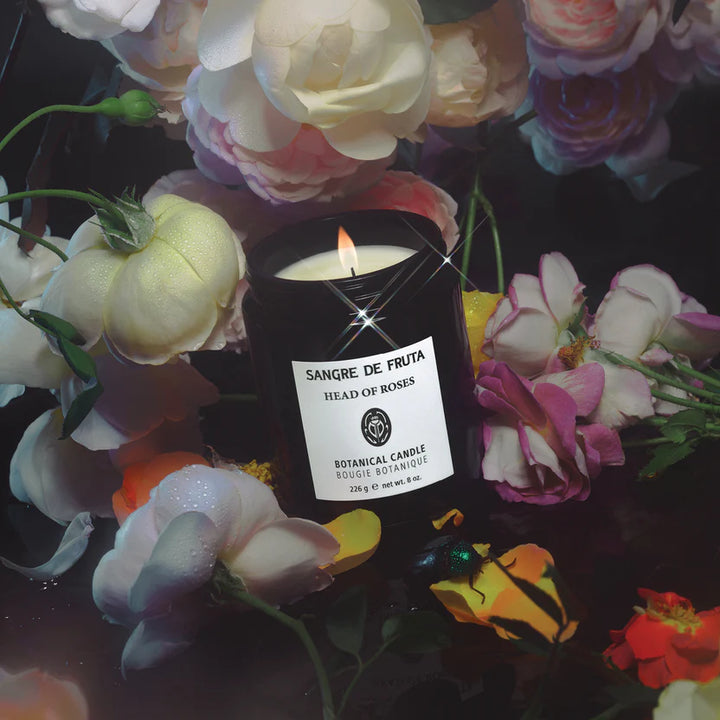 Sangre de Fruta candle with 'Head of Roses' label surrounded by colorful flowers