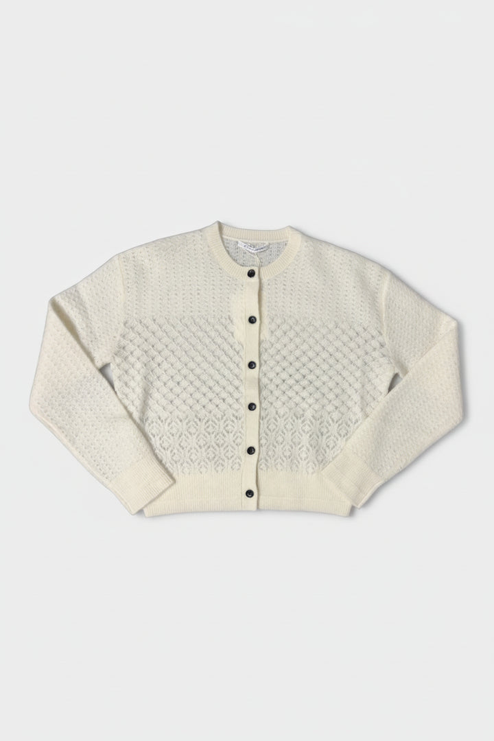 White textured cardigan with black buttons on a white background