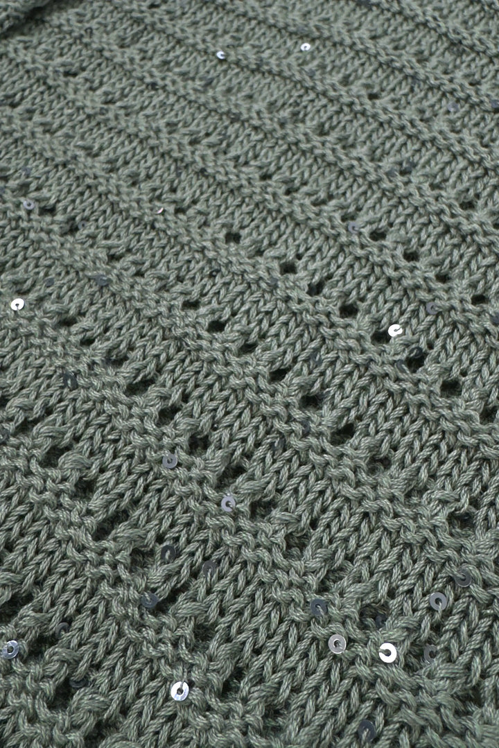 Close-up of a textured green fabric with a diamond pattern and small white beads.