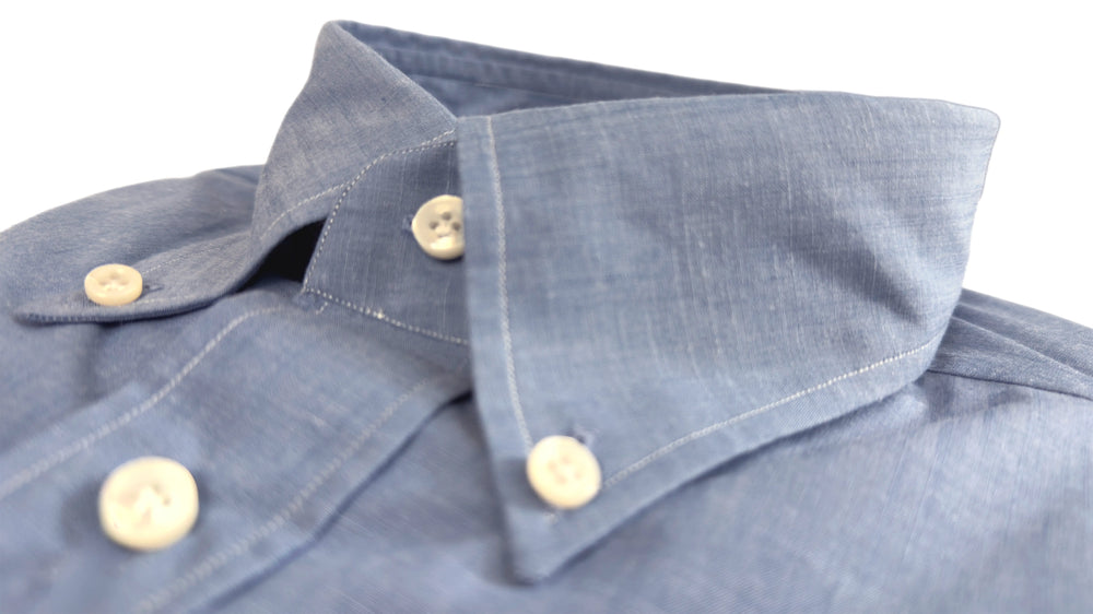 Close-up of a blue shirt collar with buttons on a white background