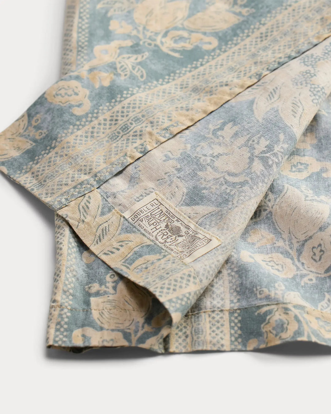 Folded fabric with a floral pattern and a visible brand label on a white background