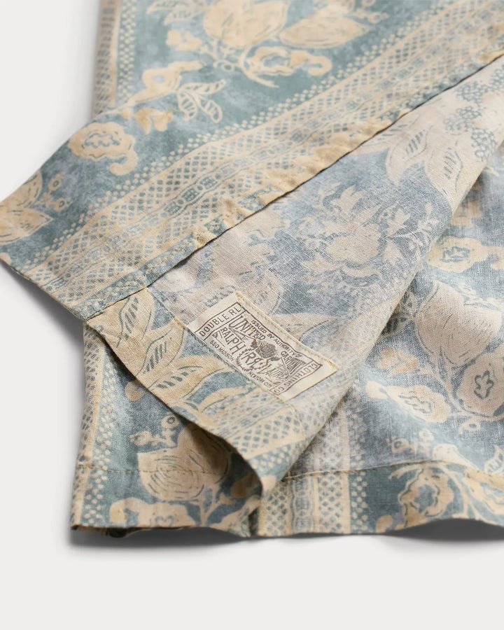 Folded fabric with a floral pattern and a visible brand label on a white background