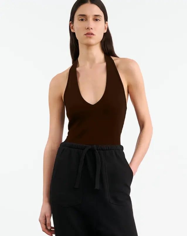Woman wearing a brown halter top and black pants on a white background