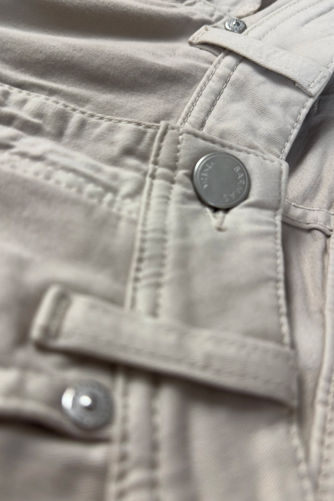 Close-up of a beige jacket with buttons and a brand logo.