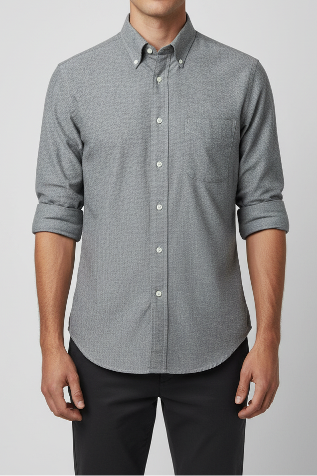 Man wearing a gray button-up shirt and black pants against a light gray background