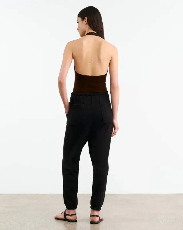 Woman wearing a brown halter top and black pants on a white background
