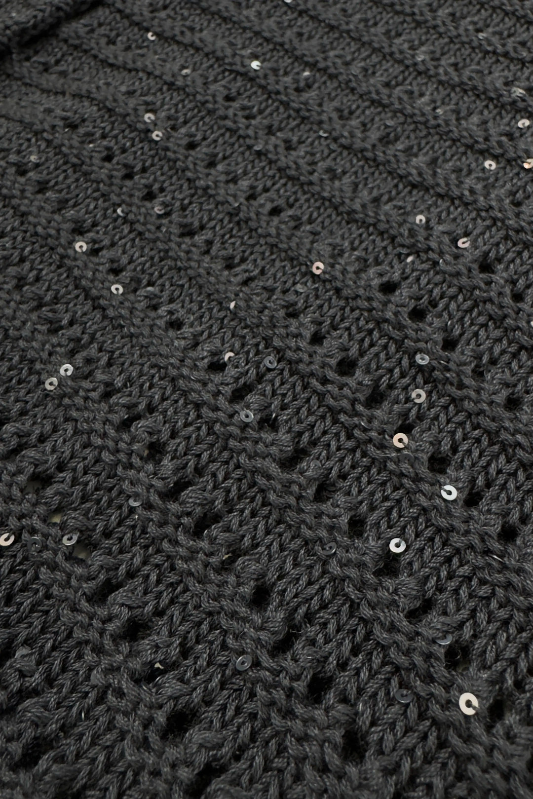Close-up of a dark gray textured fabric with small sequins.