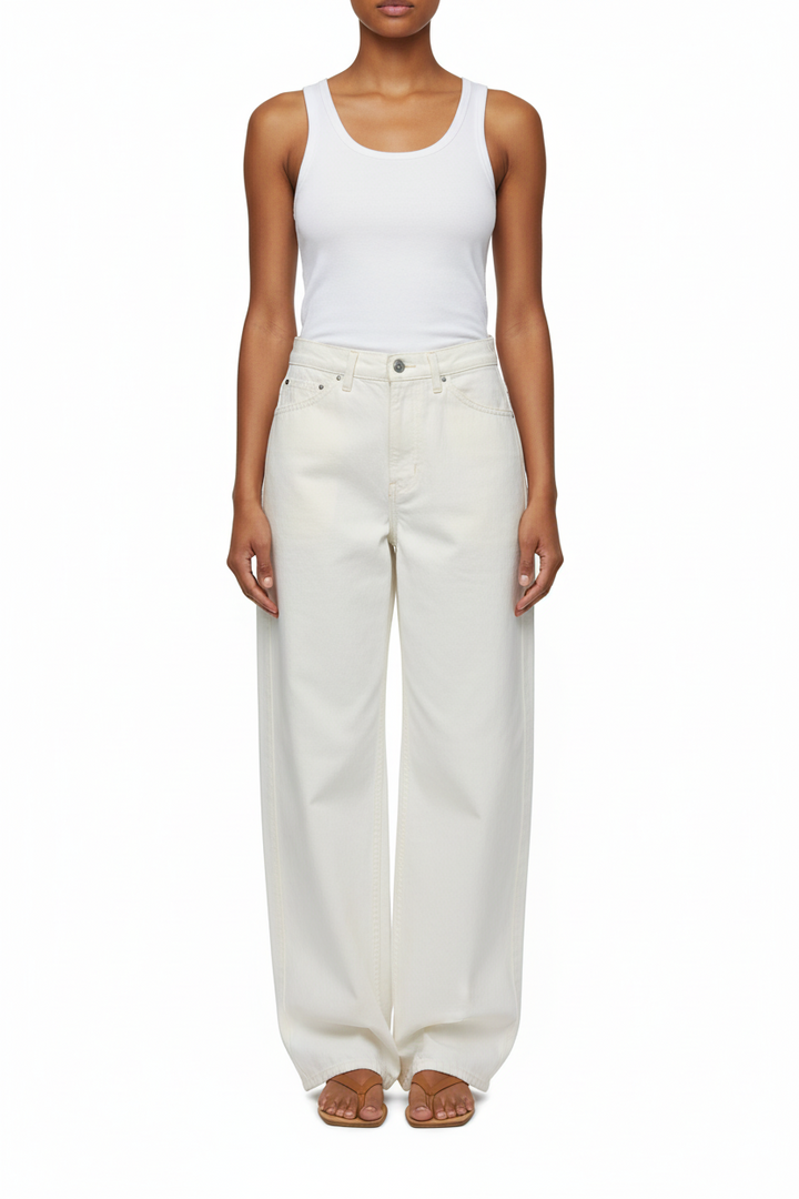 Person wearing a white tank top and cream-colored wide-leg jeans on a white background