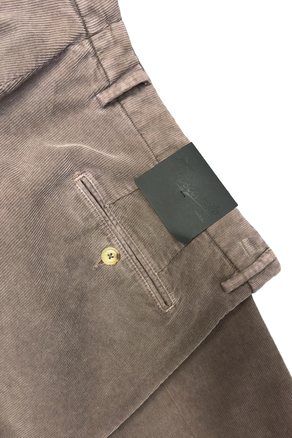 Close-up of brown pants with a brand tag on a white background