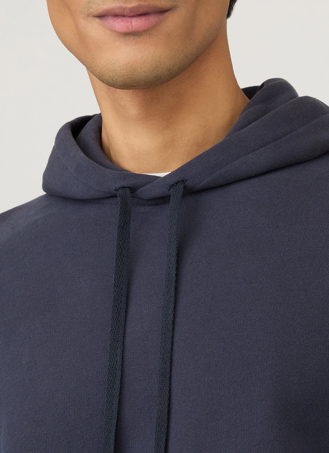 Navy blue hoodie worn by a person on a light gray background