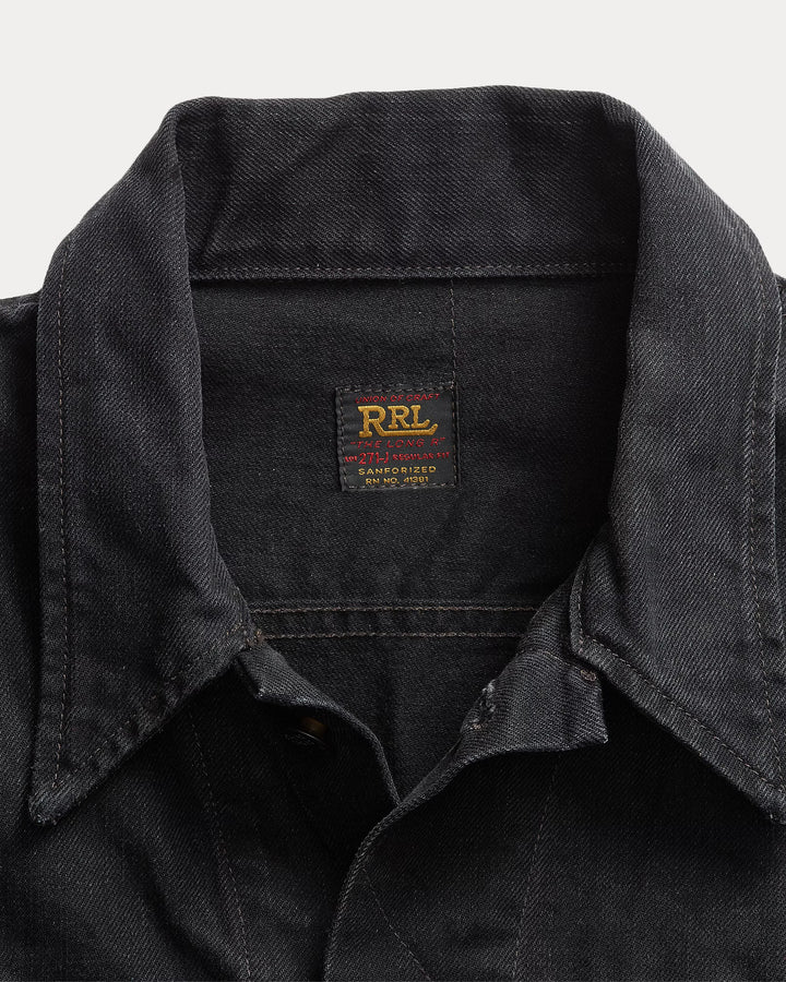 Close-up of a black shirt collar with a visible label on a light gray background