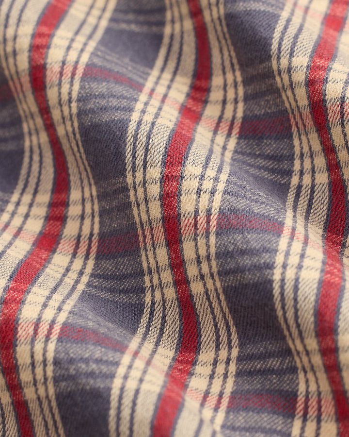 Close-up of plaid fabric with red, blue, and beige colors.