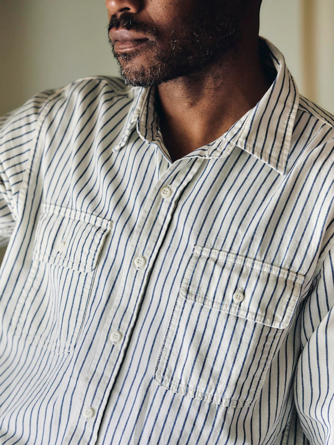 Man wearing a striped shirt with a neutral background