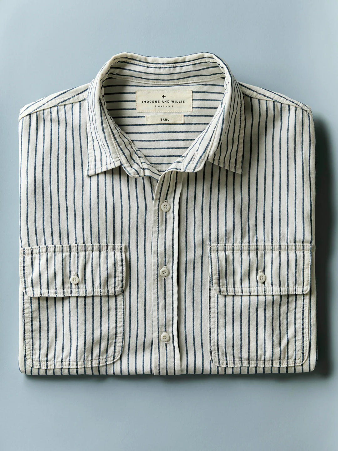 Folded striped shirt with a visible brand label on a light blue background