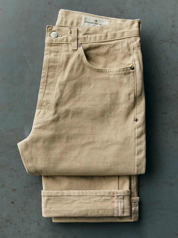 Folded beige pants on a gray surface