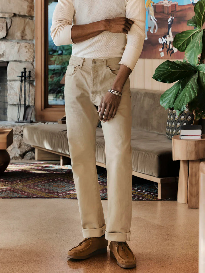 Man wearing beige pants and a cream shirt in a living room setting.