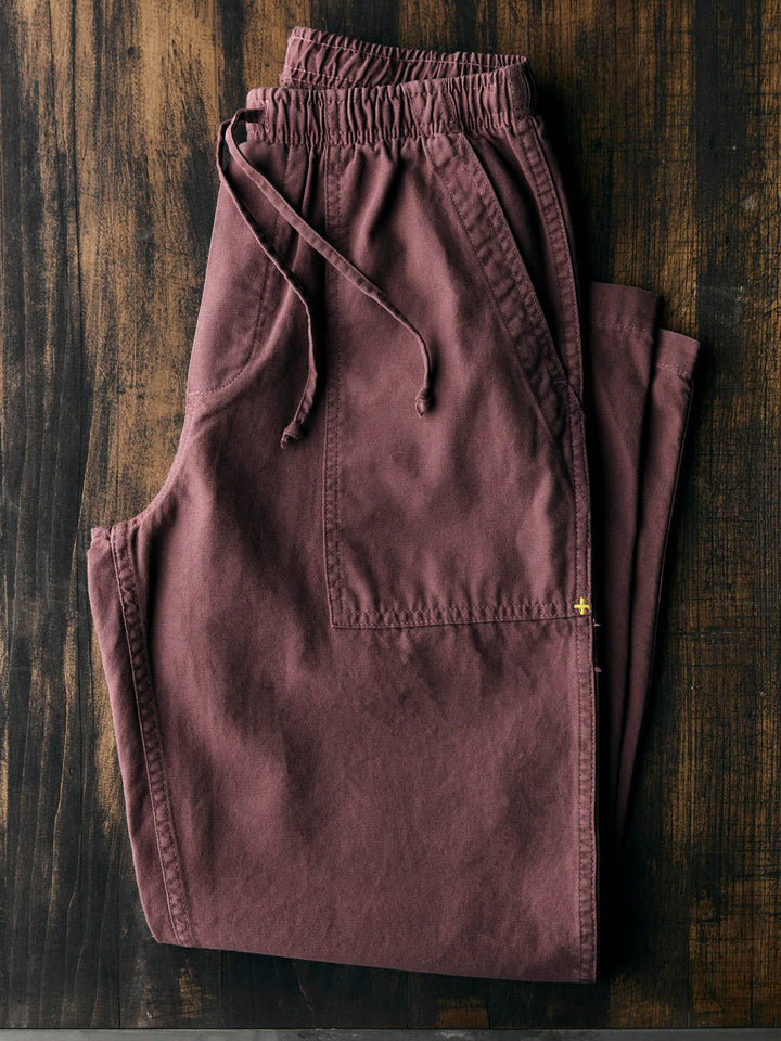 Folded maroon pants on a wooden surface
